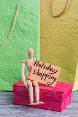 Holiday shopping background. Gift box, wooden shopaholic dummy and shopping bags, vertical image.