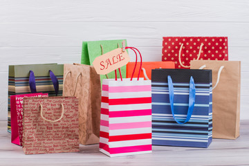 Multicolored paper shopping bags. Assortment of paper printed gift bags and card with inscription...