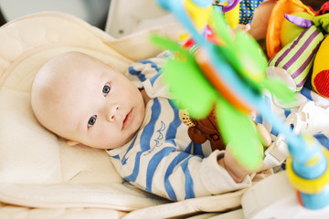 baby laying in bouncer chair and playing toy