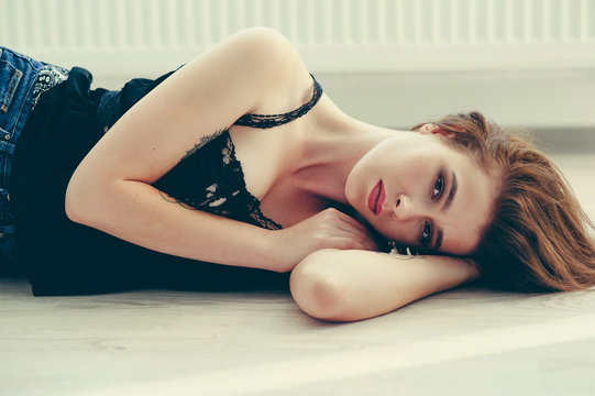 Pretty young girl wearing black shirt and blue jeans laying on the floor