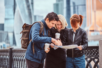 Group of tourists searching place on the map in front of skyscrapers