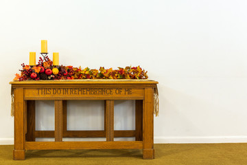 Communion table decorated for the fall with candles and colored leaves on a isolated background.