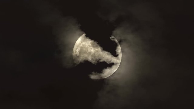 Clouds floating across the moon on a dark night