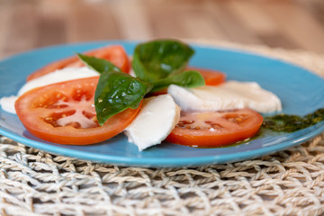 Close up of fresh tomato, cheese and basil on a plate