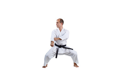 Adult active athlete trains formal karate exercises on white background