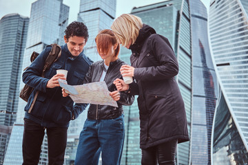 Group of tourists searching place on the map in front of skyscrapers