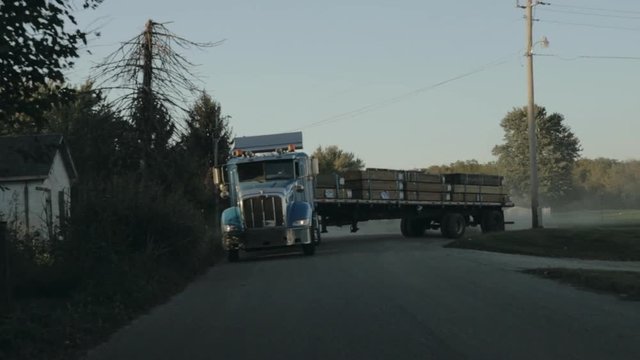 Peterbilt semi truck pulling out of yard and driving down the street front view