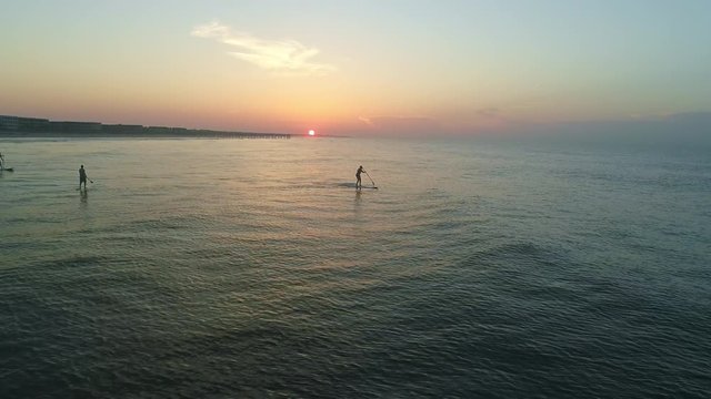 An Aerial Shot Of A Paddle Boarder At Sunrise Falling Off Paddle Board