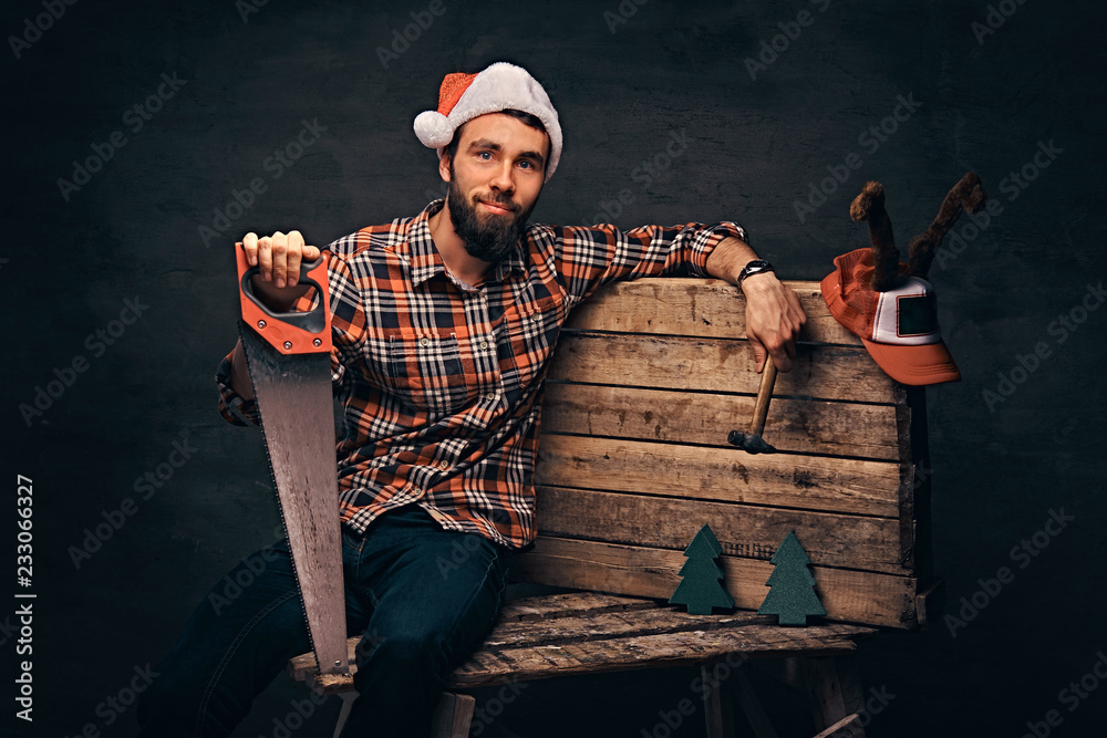 Wall mural Carpenter wearing decorated santa hat sitting on a wooden palette.