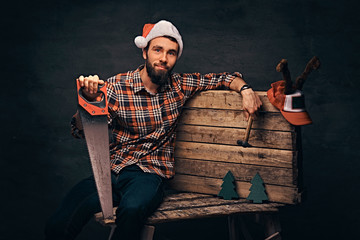 Carpenter wearing decorated santa hat sitting on a wooden palette.
