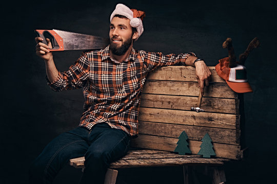 Carpenter wearing decorated santa hat sitting on a wooden palette.