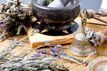 Mortar and Pestle on pentacle altar tile with dried herb bundles, brass bell, quartz crystal