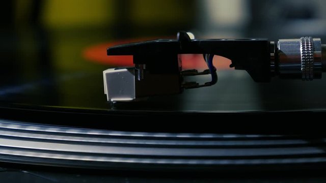 A needle is put down on the spinning black vinyl on the turntable slow motion