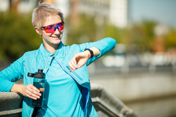 Image of sport woman with water looking at watch