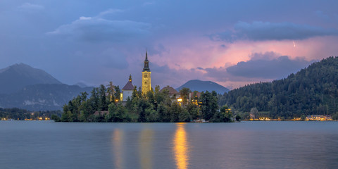 Lake bled with church under lightning sky