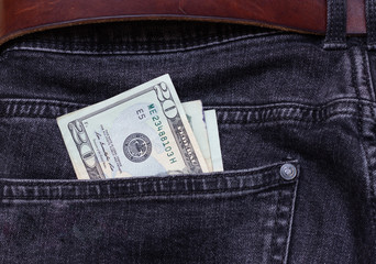 Banknote of twenty dollars sticking out of the black jeans pocket