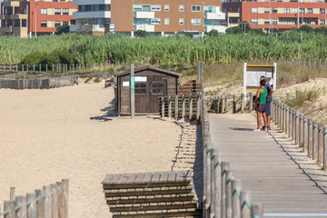 View of couple talking on pedestrian wooden walkway, near the beach