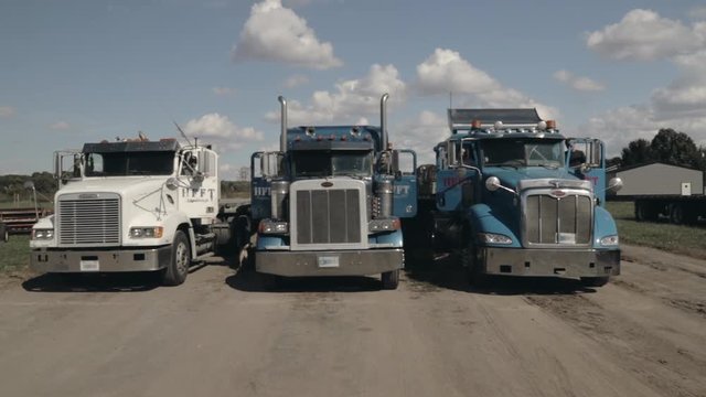 Three Semi Trucks parked side by side with all doors opening at the same time
