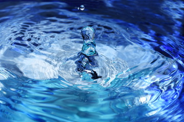 Splash and ripples in blue water liquid