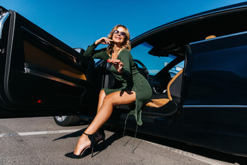 Image of blonde girl with keys in long dress sitting in car with open door