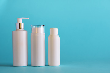 White cosmetic tubes on blue background with copy space. Skin care, body treatment, beauty concept. Banner