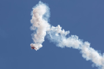 Biplane at the aerobatic show with big white smoke trail