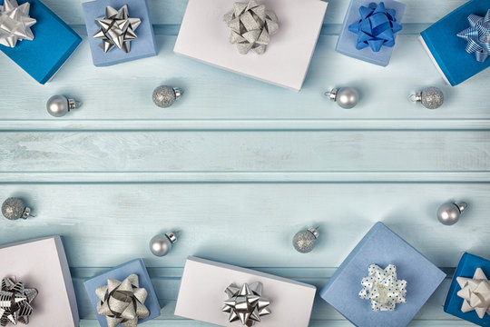Christmas frame. White and blue gift boxes decorated with silver bows. Small Christmas balls. Copy Space. Holiday layout with place for text.