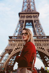 Naklejka premium Style redhead girl in red coat and bag at parisian street with view at Eiffel tower in autumn season time
