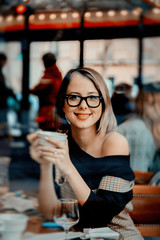 Style redhead girl in glasses with cup of coffee in parisian cafe. Autumn season time