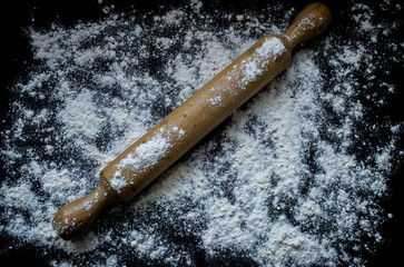 Rolling pin with flour on a black background