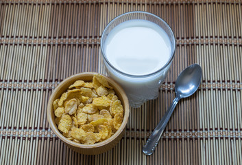 Cornflakes cereals in a bowl accompanied by a glass of milk. A healthy and typical breakfast