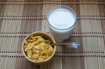 Cornflakes cereals in a bowl accompanied by a glass of milk. A healthy and typical breakfast