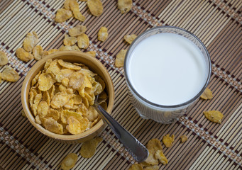 Cornflakes cereals in a bowl accompanied by a glass of milk. A healthy and typical breakfast