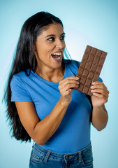 Attractive cute young woman with big bar of chocolate looking at it happy with temptation