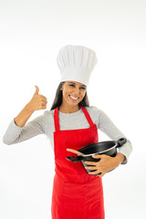 Beautiful happy young woman chef with wooden spoon pot red apron and hat making thumb up gesture