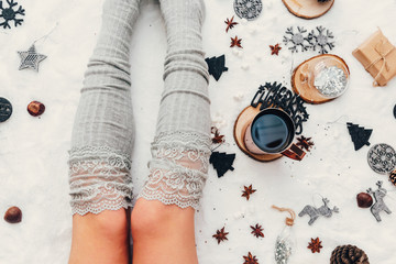  Young woman legs  with cup of coffee or cocoa. Soft light and comfy lifestyle concept. Holiday moodboard