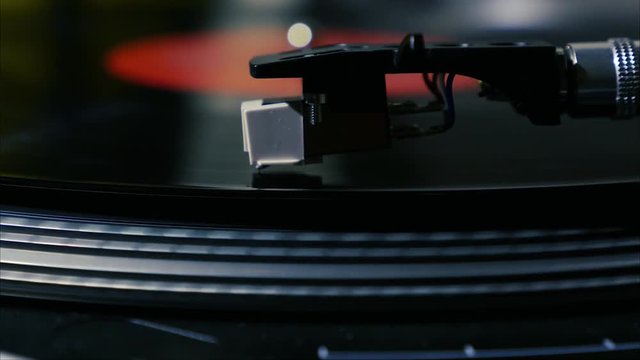 A needle is put down on the spinning black vinyl on the turntable