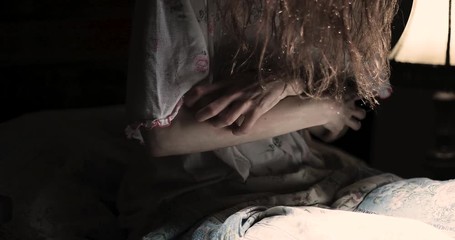 Scary girl obsessed by devil scratches in convulsions on the bed / exorcism concept / detail