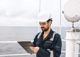Marine service technician or serviceman near VSAT terminal on deck of vessel or ship. He is filling...