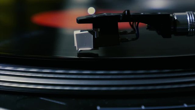 A needle is put down on the spinning black vinyl record on turntable slow motion