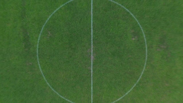 Aerial drone shot rising above football field revealing entire pitch and goals. Soccer.