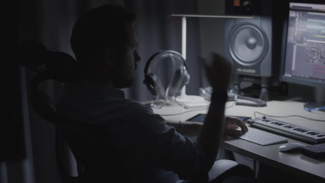 Producer / Sound engineer / musician checking a sound mix in his studio