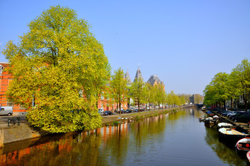 Fototapeta premium Beautiful river canal with boats and green trees in Amsterdam, Holland (Netherlands)