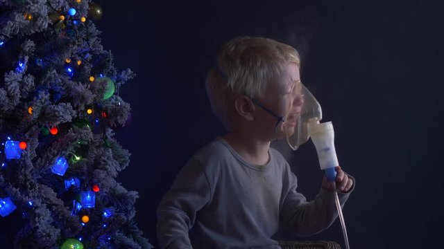 Caucasian blond child is crying from spasm of bronchitis and inhales vapors containing medications from inhaler to stop choking. Medical procedures. Respiratory medicine. Bronchitis, asthmatic problem