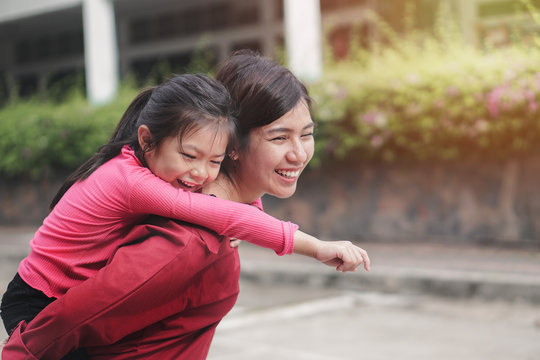 Back to school concept, Cute asian young daughter or pupil on a piggy back ride with her mother or parant at school, Selective focus.