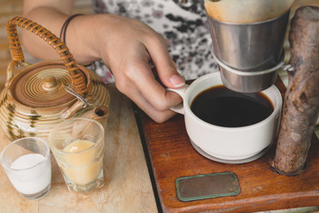 Happy asian woman holding a cup of drip coffee on wooden table,Enjoying morning coffee concept.