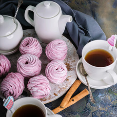 Delicious fruit marshmallow and flavored tea in white cups. Close-up