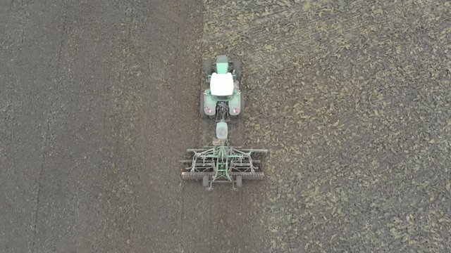 Aerial top view shot of tractor & speed discs moving across field.