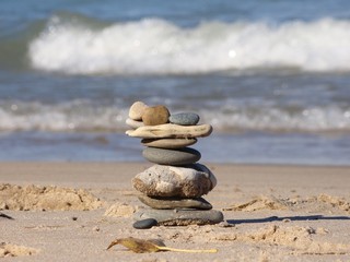 Fototapeta na wymiar Rock art balance zen on sandy beach with waves in background