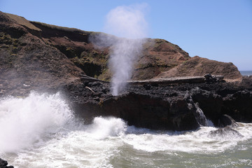 Spouting Horn natural phenomena at Cape Perpetua headland. Fountain of steam and salt water erupts from a hole in a basalt rock under the pressure of high tide, Oregon Coast